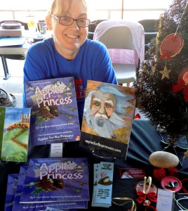 michelle buvala sits at a table of books from the apples for the princess series