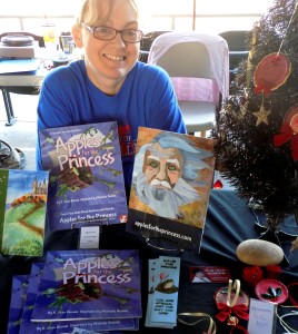 michelle buvala sits at a table of books from teh apples for the princess series